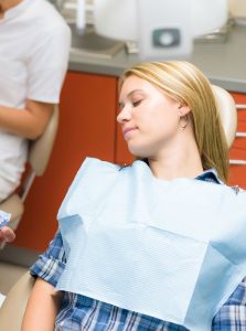 An image of a woman resting in a dental chair with dental sedation to relax her