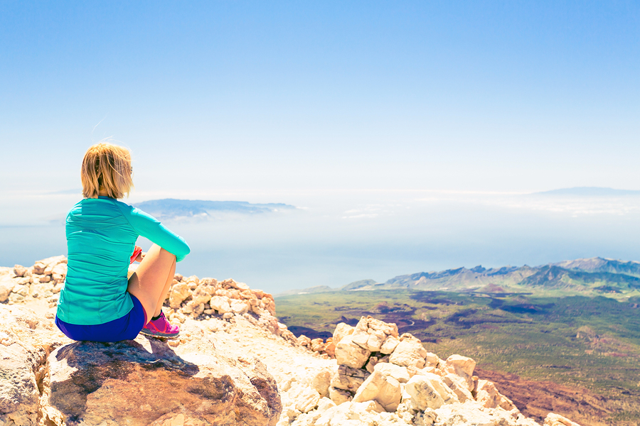 Young woman looking and meditation outside natural beautiful inspirational landscape environment fitness and exercising motivation and inspiration in sunny mountains over blue sky and ocean sea.
