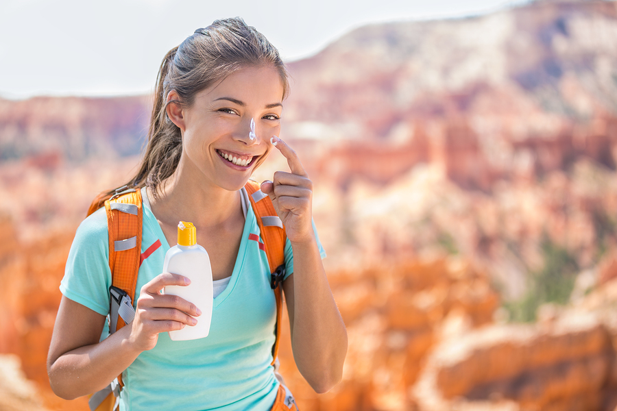 Hiker sunscreen. Woman hiking putting sunblock lotion outdoors d