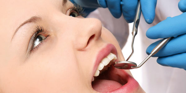 Woman practicing good oral hygiene by getting teeth examined by dentist