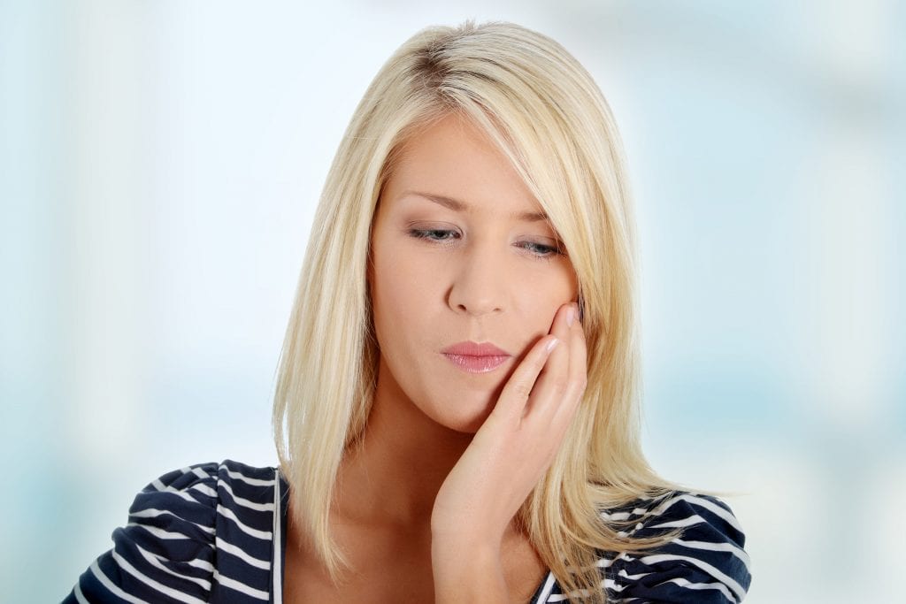 Young woman in pain is having toothache.
