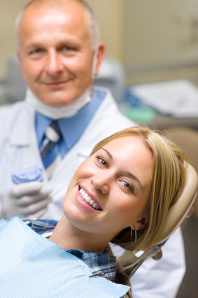 Woman smiling from the dental chair with her dentist standing nearby